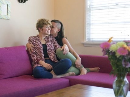 Caucasian lesbian couple kissing on sofa
