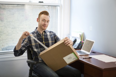 Caucasian businessman opening package in office