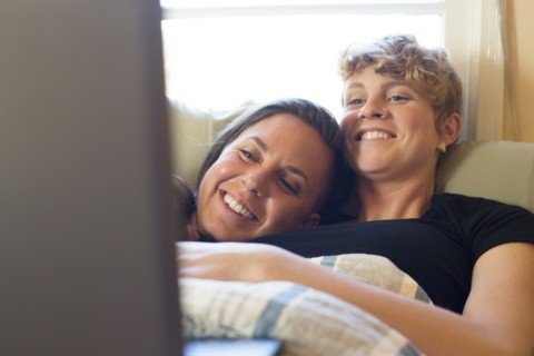Caucasian lesbian couple cuddling in bed