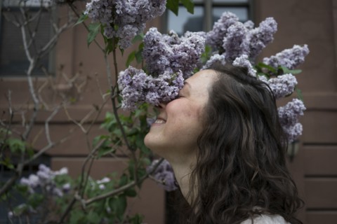 Caucasian woman smelling flowers on city street