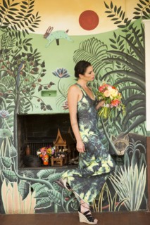 Woman wearing dress matching wallpaper