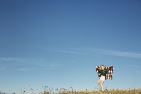 Caucasian woman playing with scarf on hilltop