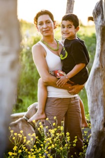 Hispanic mother carrying son in garden