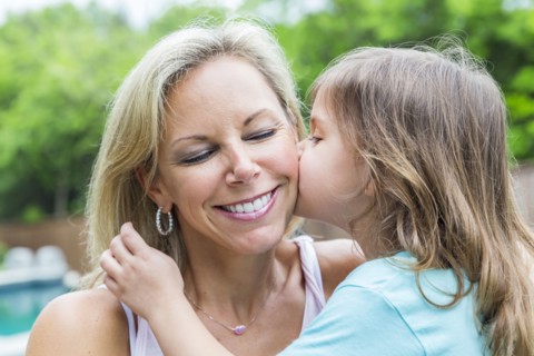 Caucasian girl kissing mother in backyard