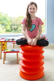 Caucasian girl sitting cross-legged on stool in playroom