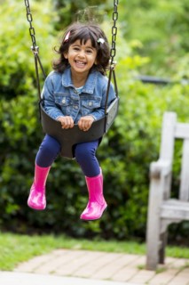 Smiling girl playing in swing at playground