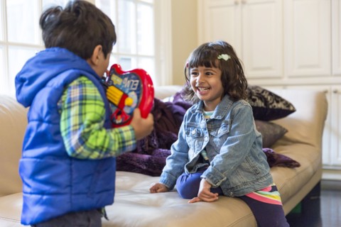 Brother and sister playing with toy in living room