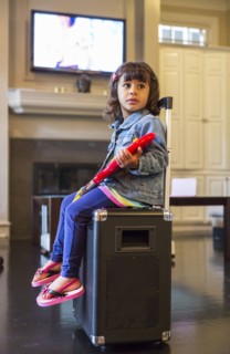 Girl playing toy guitar on amplifier in living room