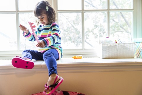 Girl playing with toys in windowsill