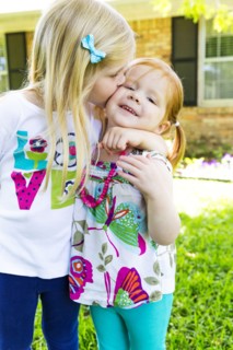 Caucasian sisters kissing in backyard