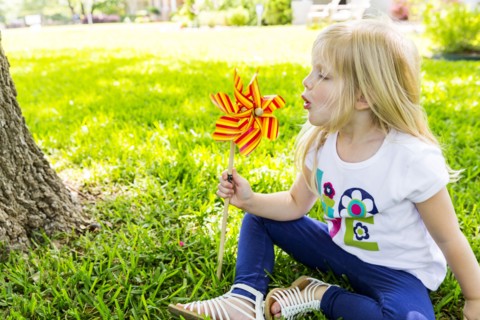 Caucasian girl playing with pinwheel in backyard