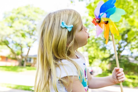 Caucasian girl playing with pinwheel in backyard