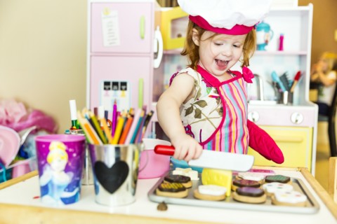 Caucasian girl playing with toy kitchen