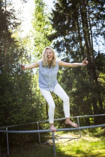Woman jumping from metal structure in backyard