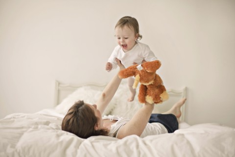 Caucasian mother playing with baby on bed