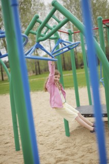 Caucasian girl hanging from structure in playground