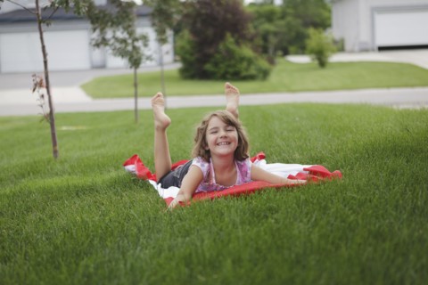 Caucasian girl laying on lawn in suburban neighborhood