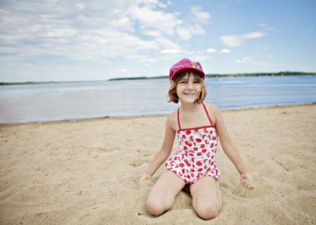 Caucasian girl kneeling on beach