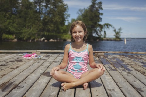 Caucasian girl sitting on wooden dock over lake