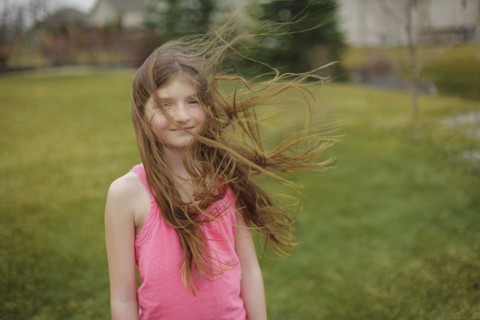 Hair of Caucasian girl blowing in wind in backyard