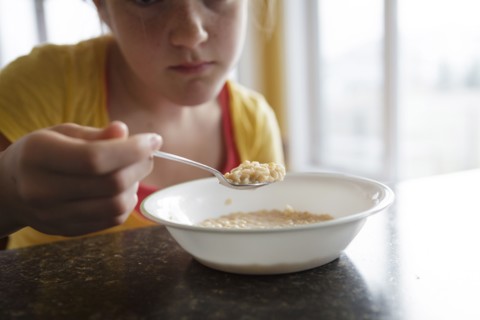 Caucasian girl eating breakfast at table