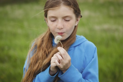 Caucasian girl blowing dandelion outdoors