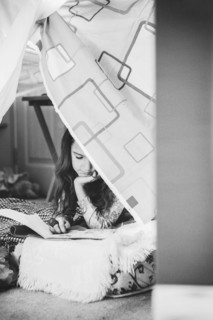 Caucasian girl reading in pillow fort