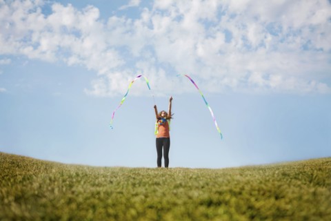 Caucasian girl playing with ribbons on hilltop