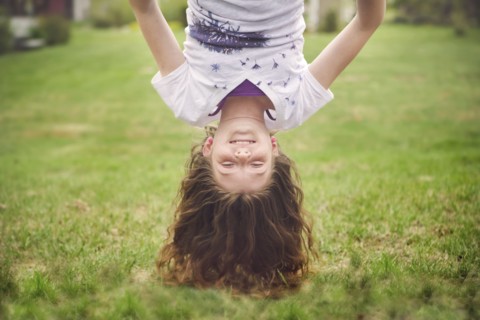 Caucasian girl hanging upside down in backyard