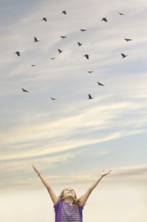 Caucasian girl cheering under flock of birds
