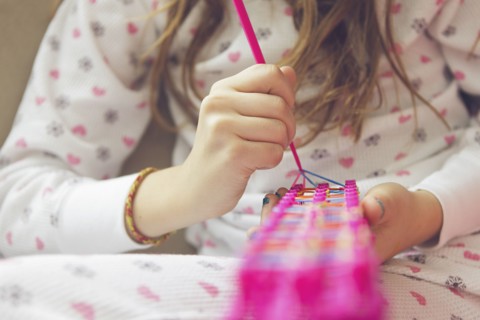 Caucasian girl knitting with rainbow loom