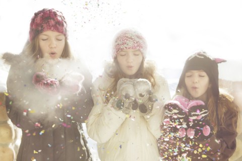 Caucasian girls blowing snow off mittens