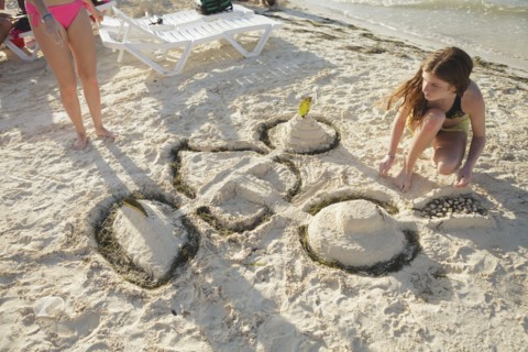 Caucasian teenage girl building sandcastle on beach
