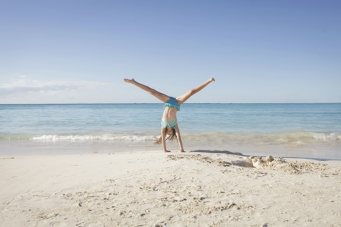 Caucasian girl doing cartwheel on beach
