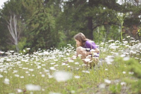 Caucasian girl crouching in field of flowers
