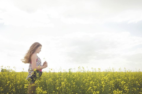 Caucasian teenage girl standing in field of flowers