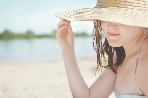 Caucasian teenage girl wearing sun hat on beach