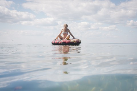 Caucasian teenage girl floating in inner tube on lake