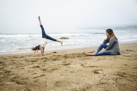 Hispanic mother and daughter playing on beach