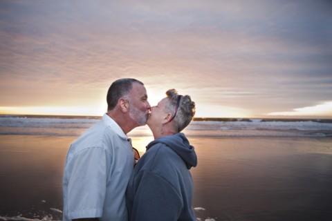 Caucasian couple kissing on beach at sunset