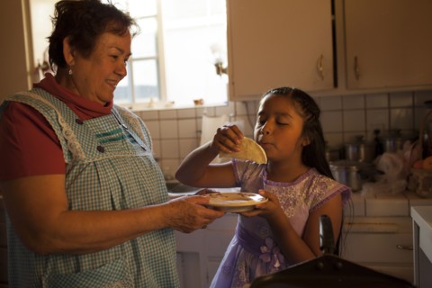 Hispanic woman cooking for granddaughter in kitchen