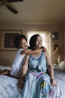 Grandmother and granddaughter hugging on bed