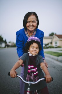 Grandmother teaching granddaughter to ride bicycle on suburban street