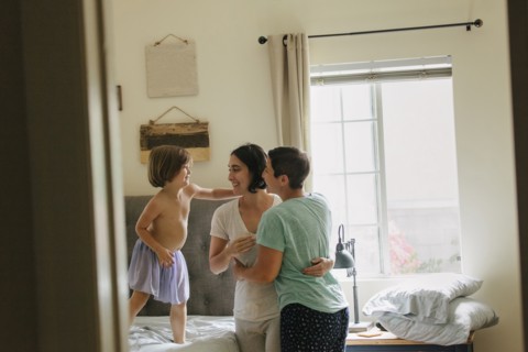 Caucasian family hugging in bedroom