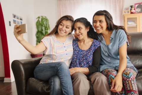 Grandmother and granddaughters taking selfie on sofa