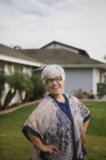 Older woman standing with hands on hips in backyard