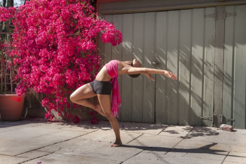 Woman practicing yoga near flowers and fence