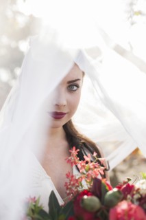 Caucasian bride holding bouquet under veil