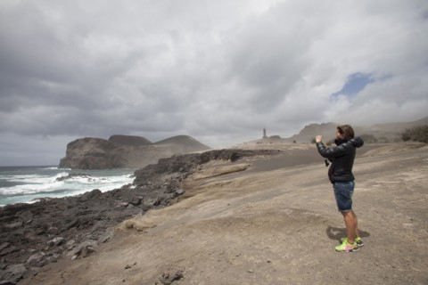 Caucasian woman photographing rocky beach