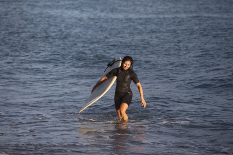 Hispanic surfer carrying surfboard in ocean
